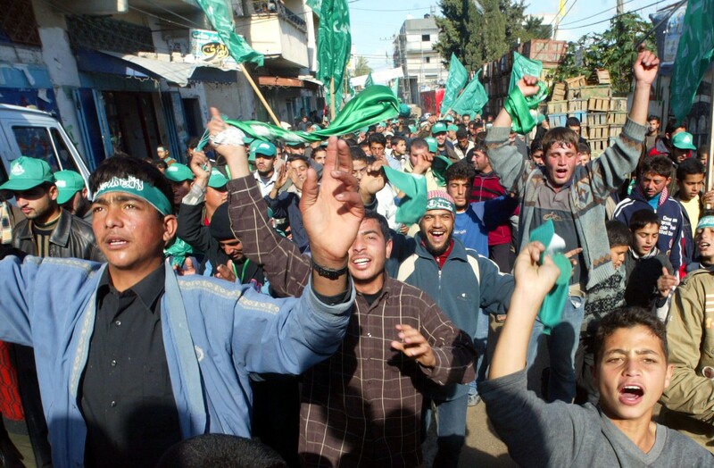 Young men wearing green hats and headbands rmarch on a street