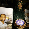 Woman holds a cake, surrounded by posters of prisoner