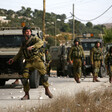 Soldier next to jeep throwing grenade. More soldiers nearby.