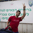 Young man gives carrying duffel bag gives victory gesture with his hand