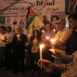 Crowd hold candles in tent covered with posters of political prisoners