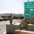 Photo shows highway sign for Route 443 with group of Israeli soldiers forming roadblock in background