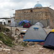 Photograph shows camping tents in front of old church built of stone