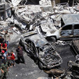 Aerial view of people standing near burnt-out cars and shelled buildings