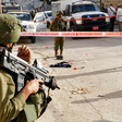 An Israeli soldier holding a rifle stands guard at a site marked by police tape