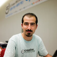 Smiling young man with goatee wearing Creative Commons t-shirt is seen from chest up