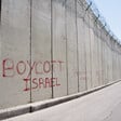 Red graffiti on the Israeli apartheid wall dividing the East Jerusalem neighborhood Ras al-Amud from the West Bank town of Abu Dis reads, "Boycott Israel", on 26 March 2012. 