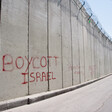 Red graffiti on the Israeli apartheid wall dividing the East Jerusalem neighborhood Ras al-Amud from the West Bank town of Abu Dis reads, "Boycott Israel", on 26 March 2012.