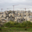 Photo shows construction cranes towering over multi-story buildings in an Israeli settlement