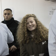 Ahed Tamimi, wearing prison uniform, smiles while surrounded by police