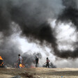 Landscape view of protesters against thick plumes of smoke from burning tires