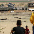 Photo shows backs of small children watching Israeli soldiers roll out barbed wire fence