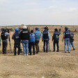 Palestinian journalists wearing press vests stand in a row at the Gaza march. 