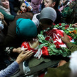 Women and girls mourn over body of youth wrapped in PFLP flags with a wreath placed on his torso