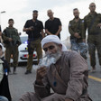 Palestinians sit near Israeli police during an early morning raid. 