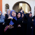 A group of mourning women stand in front of arched doorway