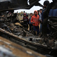 Boys look at wreckage of burned-out vehicle