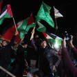 Young men wave the national flag and the Hamas flag at night