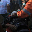 An emergency medic leans over a youth laying on a stretcher with his head wrapped in gauze