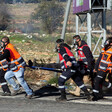 Six paramedics, some wearing gas masks, carry a person on a stretcher