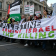 Marching near the British Parliament, protesters hold a large banner that says "Free Palestine, Stop Arming Israel, Stop the Killing"