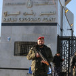 Men in military uniform carrying rifles stand in front of Rafah crossing gate