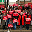 A group of Labour activists hold red signs in support of their prospective candidate for Member of Parliament.