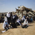 Women sit in front of ruins of demolished home. 