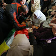 Men and women crowd around body shrouded in Palestine flag