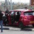 Men stand around car behind police tape