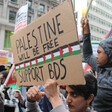 A protester holds a sign that says Palestine will be free, support BDS.