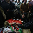 People stand and kneel around body shrouded in Palestine flag