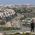 A soldier stands in front of settlement houses