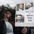 A man holds sign with pictures of Ilhan Omar and Hitler