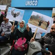 Man and woman using wheelchairs hold posters of double amputee holding Palestine flag