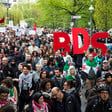 Hundreds of people march, some with signs that say "BDS"