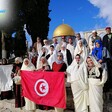 People hold the Tunisian flag near the Dome of the Rock. 