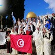 People hold the Tunisian flag near the Dome of the Rock.