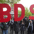 Protesters hold up big letters that spell BDS 