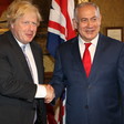 Two men shake heads in front of British and Israeli flags