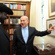 A man points to a framed picture as another looks on