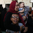 Woman embraces crying children in crowded room