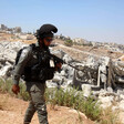 Soldier walks beside demolished building