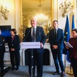 Man stands at podium with other people around him