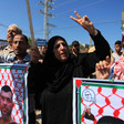 Palestinians hold banners, make peace sign with their hands