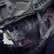 Soldier wearing helmet looks at gun. 