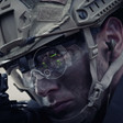 Soldier wearing helmet looks at gun. 