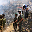 Young men in military uniform and civilian clothing stand on hillside