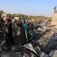 Woman throws her hands in the air while standing on rubble