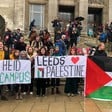 People holding signs and a Palestinian flag